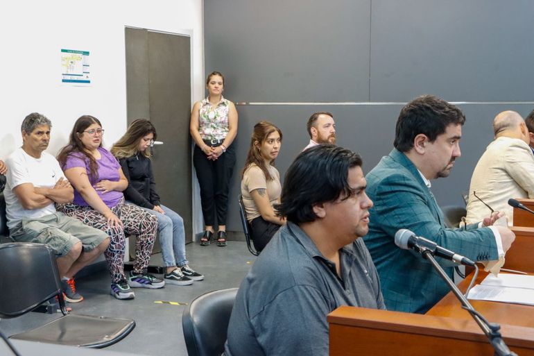 El acusado en primer plano junto al defensor Oficial Marcelo Caraballo. Atrás los allegados a las víctimas. 