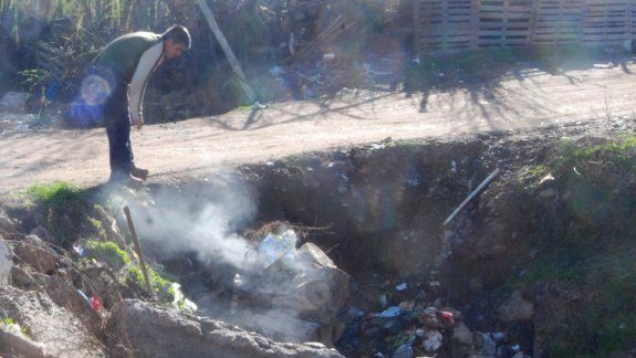 Botellas y residuos domiciliarios flotan sobre el agua pestilente.
