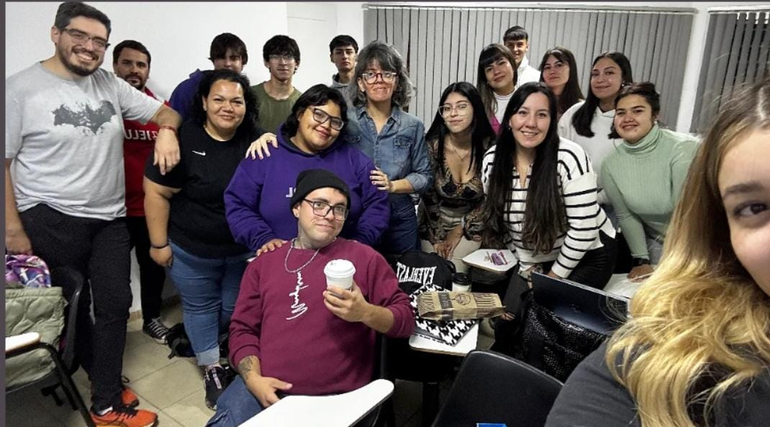 La profe Silvina abraza a Narella -buzo violeta-, que a la vez apoya sus brazos en los hombros de Elvis -gorrito Negro- en medio del aula.