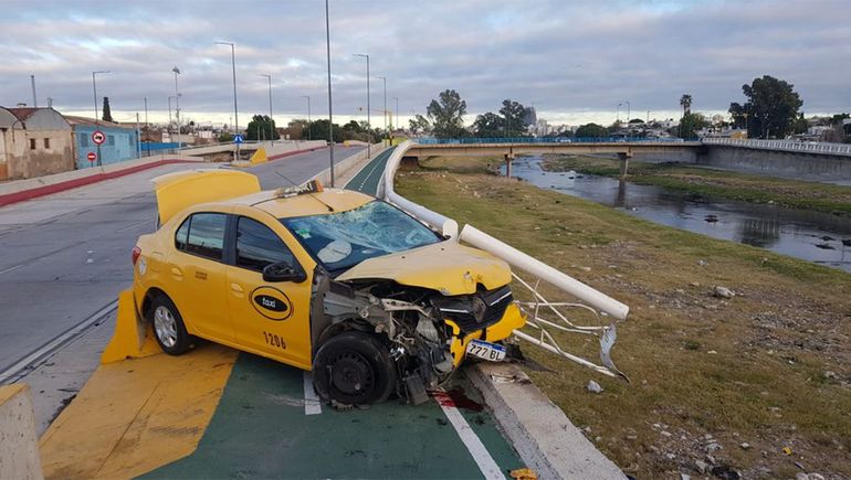 Un taxi chocó a una moto y quedó colgando de un puente: una persona murió