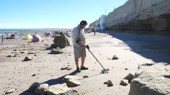 El turista busca tesoros en la playa con un detector de metales