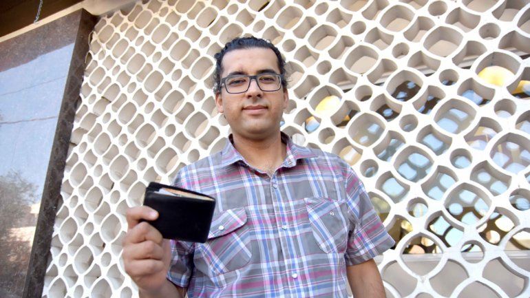 Pablo Serrano muestra la billetera que halló en Neuquén. Su novia cipoleña lo ayuda en la búsqueda.