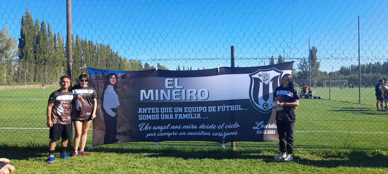 Henry y familia posan junto a la emotiva bandera que les dedicó el equipo donde juega en el Don Pedro.